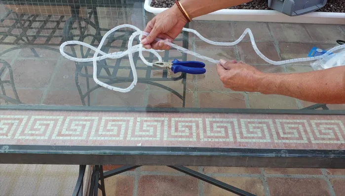 Carefully position and tie the orchid to the hanger, ensuring it hangs securely without spreading.