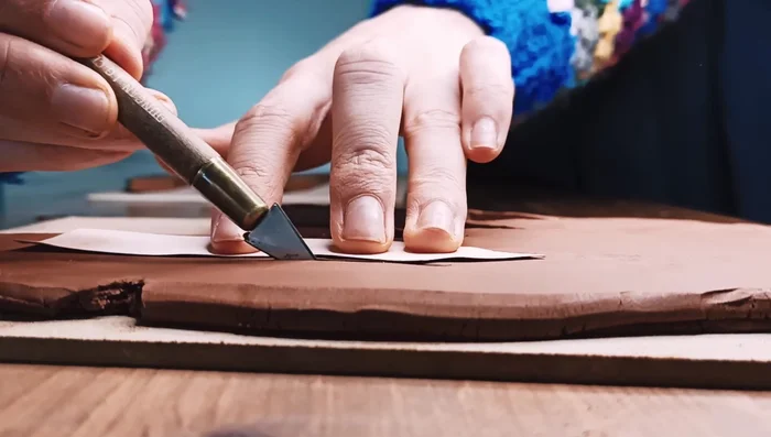 Smooth the edges and surfaces of the cut-out clay pieces using water, your fingers, or a sponge. Remove any irregularities.