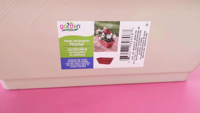 Make a fancy planter by cutting the lip off a Dollar Tree rectangle planter, constructing a box from wood shelves, and adding styrofoam, moss, and flowers.