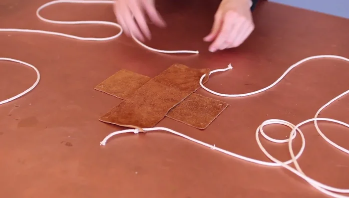 Repeat step 3 with a second cord on the opposite side of the same leather piece.