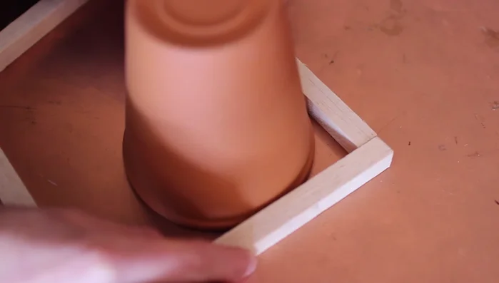 Sand down the edges if needed. Build a square around the upside-down pot to ensure a snug fit.